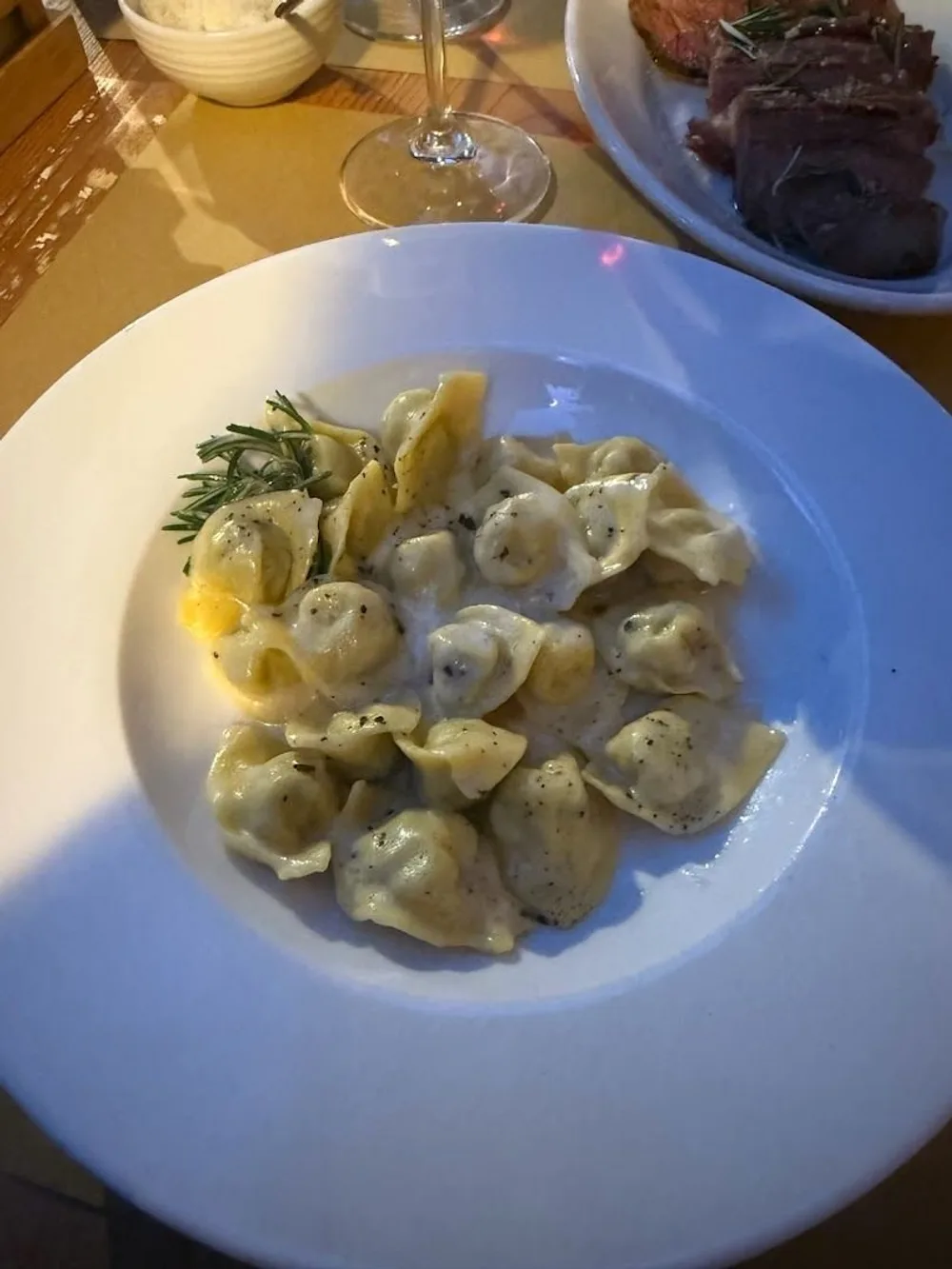 Cappellacci al burro e rosmarino in un piatto bianco