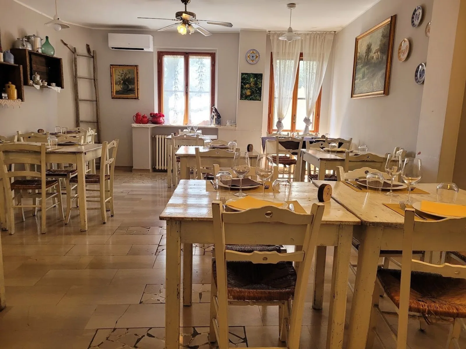 La sala dell’osteria con tavoli in legno chiaro e sedie impagliate
