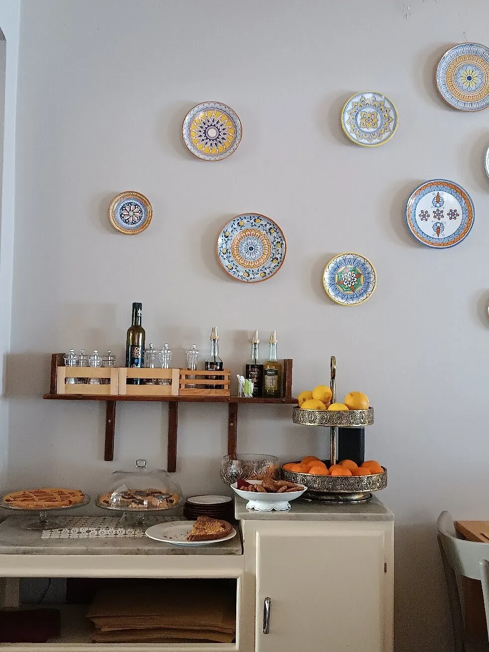 Piatti in ceramica dipinti alle pareti della sala, accanto al bancone dei dolci