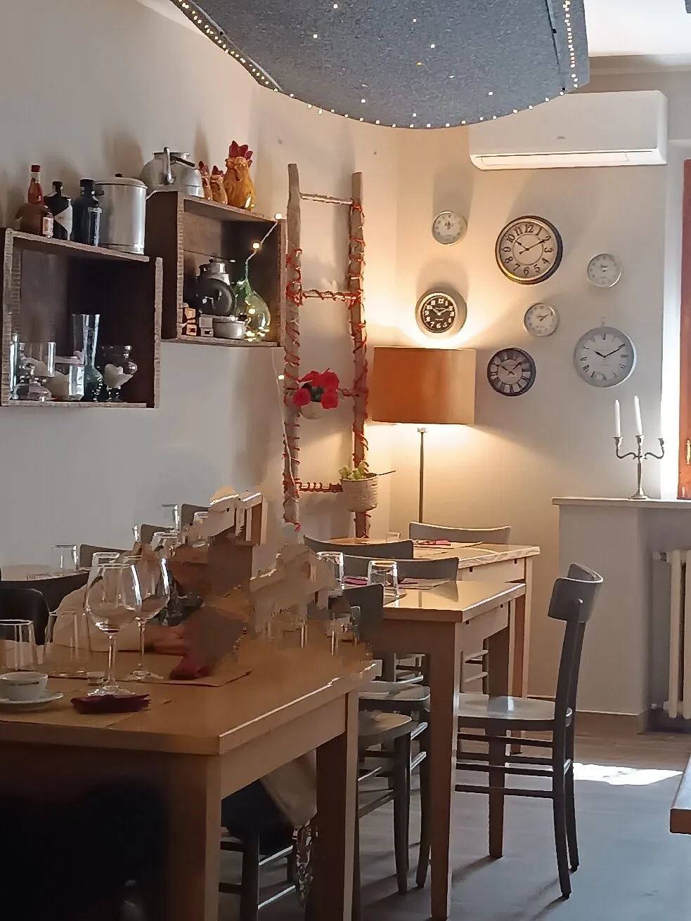 I tavoli in legno della sala, con la luce calda di una lampada