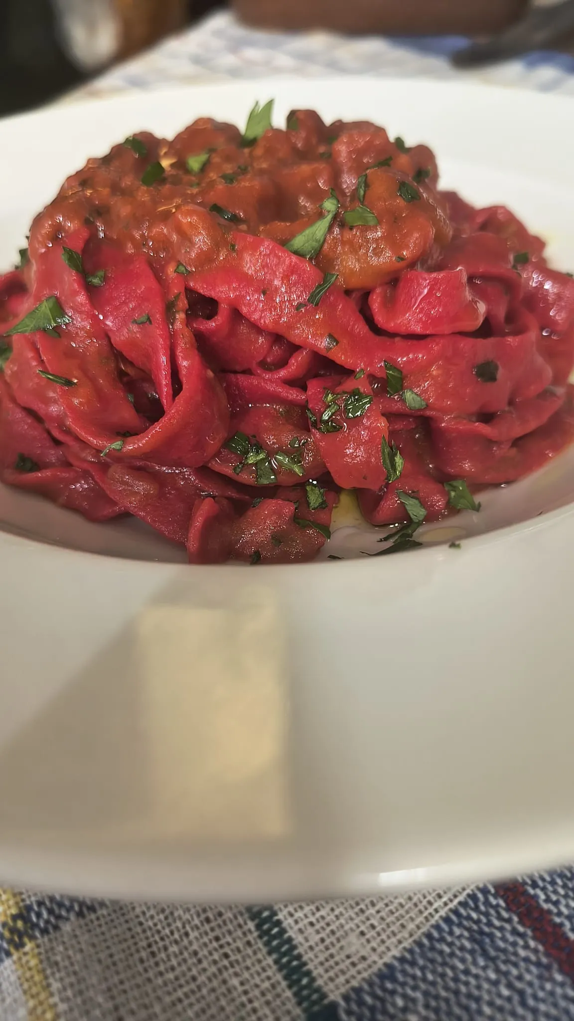 Tagliatelle rosse al ragù in un piatto bianco
