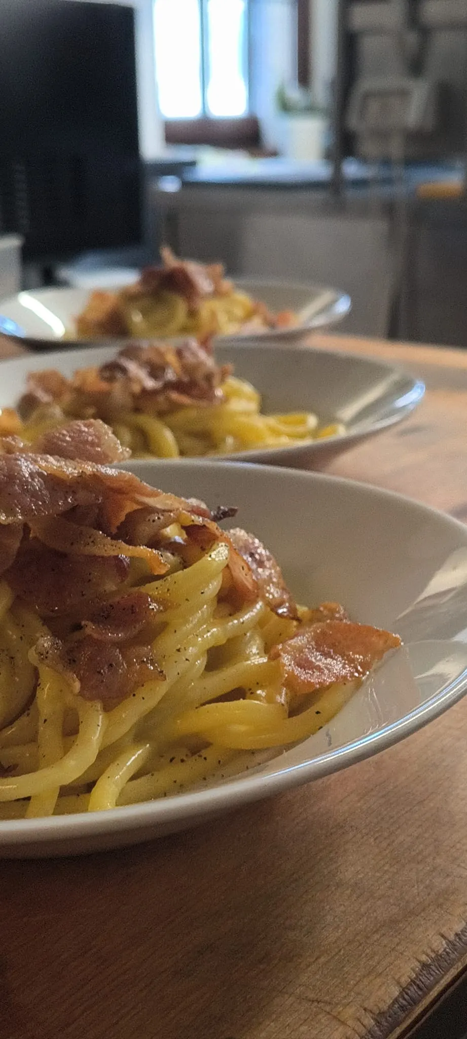 Piatti di pasta fresca con guanciale croccante, appena impiattati