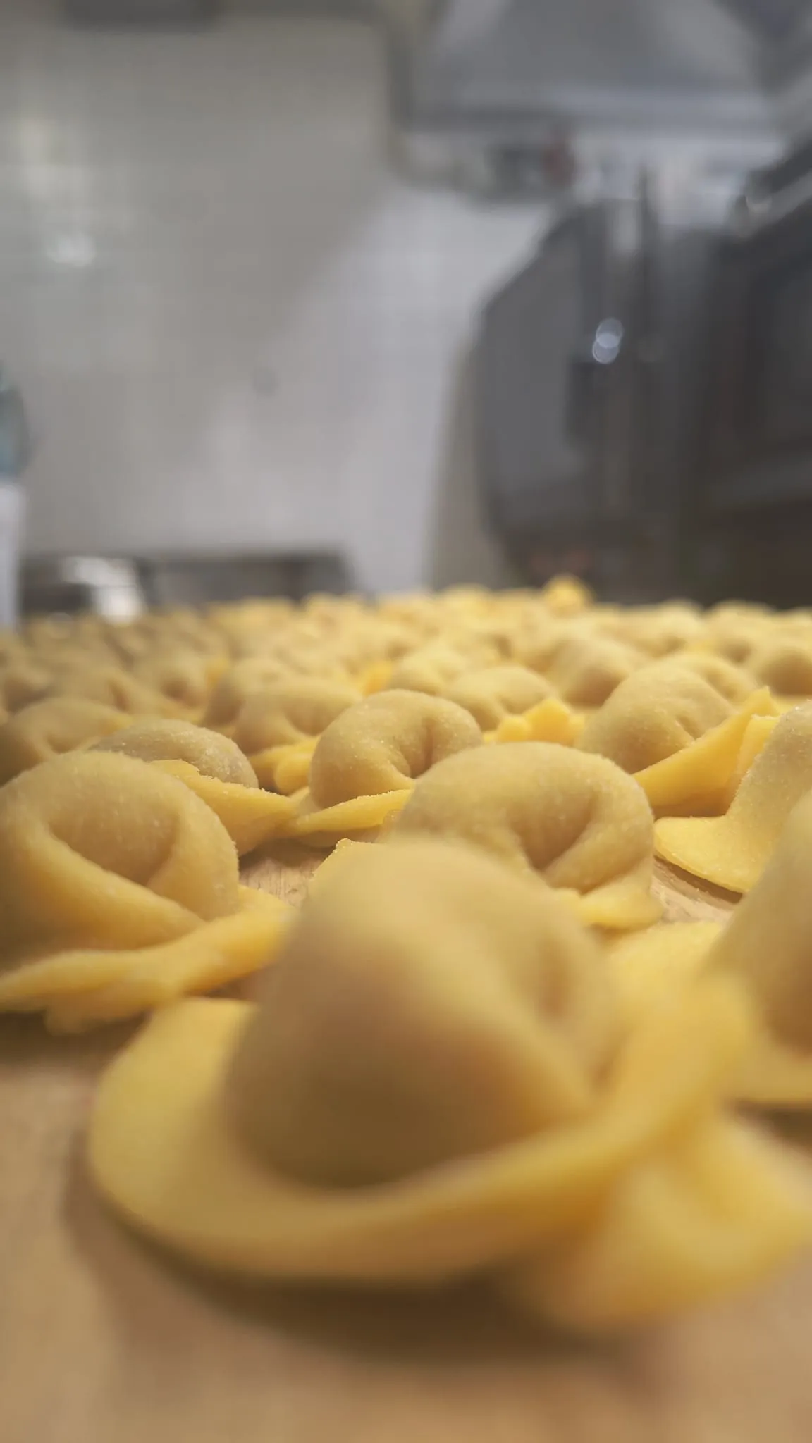 Primo piano di un tortello fresco, con gli altri sfocati dietro